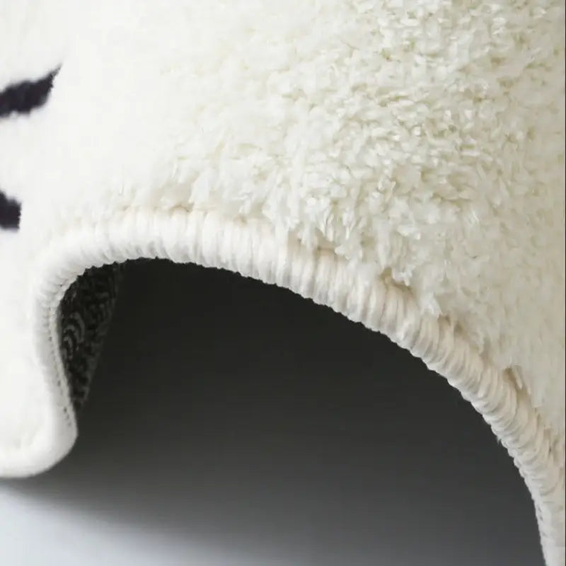 Tapis original blanc, forme irrégulière, design artistique,détail et finitions du tapis.